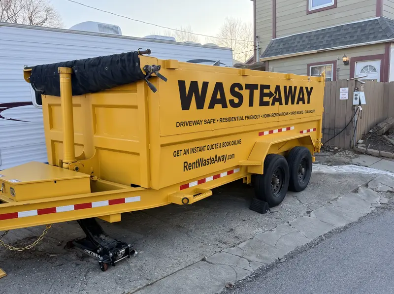 Waste Away dumpster in a driveway with wheel chocks